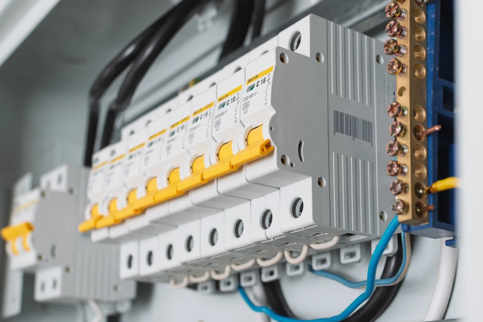 Service d'entretien de l'électricité et de l'électricité, ingénieur utilisant un outil de mesure de l'équipement pour vérifier la tension du courant électrique au terminal de disjoncteur et à la carte principale de distribution de l'énergie du câblage