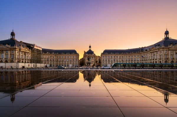 Un électricien professionnel en action à Bordeaux, intervenant sur une installation électrique (panneau, prise ou câblage) dans un environnement urbain ou résidentiel bordelais typique. L'électricien porte l'équipement de sécurité approprié et manipule des outils professionnels. L'image peut subtillement suggérer le contexte urbain bordelais (architecture locale, rue de la ville) sans être intrusive. Idéalement, on pourrait voir un vélo professionnel garer à proximité, reflétant l'engagement écologique de l'entreprise en mobilité douce.